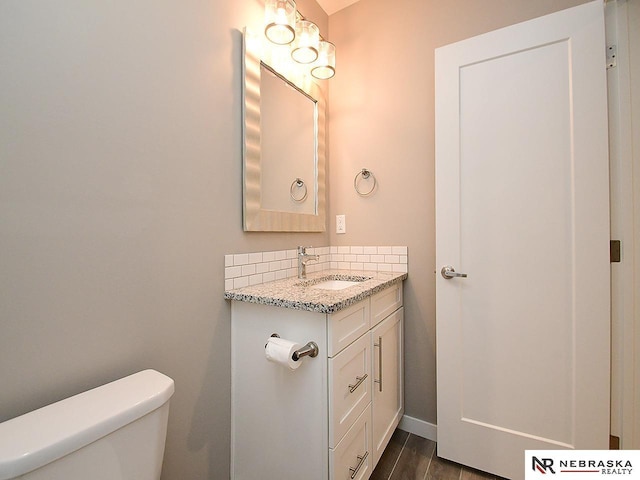 bathroom featuring hardwood / wood-style flooring, vanity, toilet, and backsplash