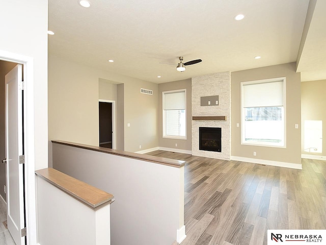 unfurnished living room with light hardwood / wood-style flooring, a fireplace, plenty of natural light, and ceiling fan