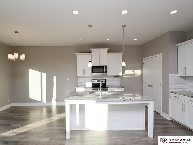 kitchen with light stone countertops, an island with sink, white cabinets, and appliances with stainless steel finishes