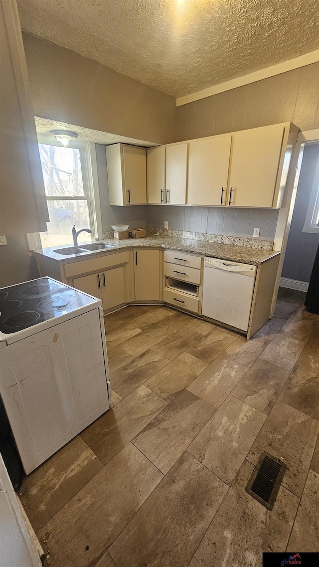 kitchen with cream cabinets, sink, a textured ceiling, and white appliances