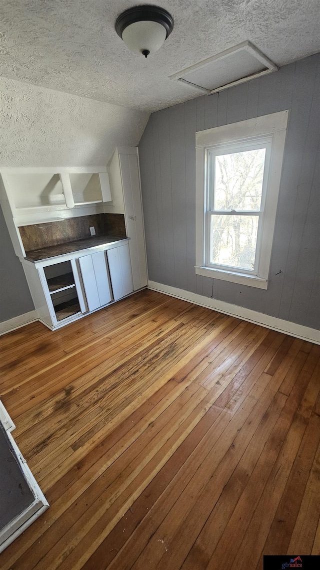 bonus room featuring lofted ceiling, light hardwood / wood-style flooring, and a textured ceiling