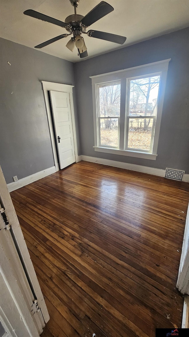 unfurnished bedroom with ceiling fan, dark hardwood / wood-style floors, and multiple windows