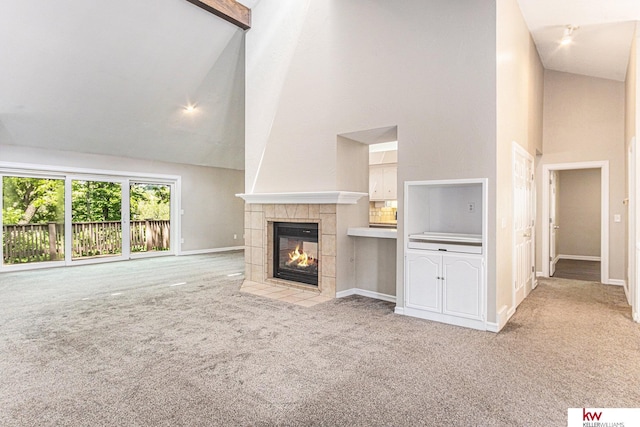 unfurnished living room with light carpet, a tiled fireplace, and high vaulted ceiling