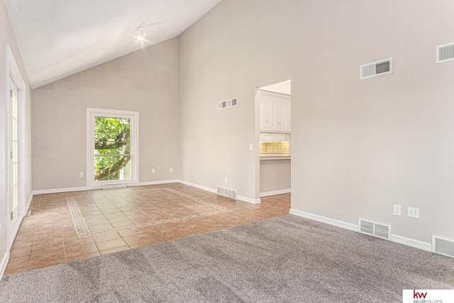 tiled empty room featuring high vaulted ceiling