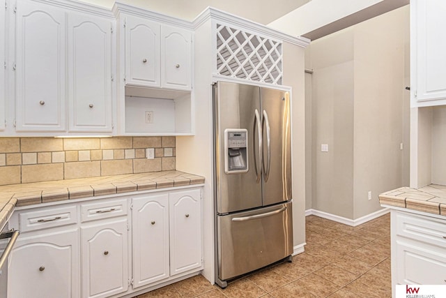 kitchen with white cabinetry, tile countertops, backsplash, and stainless steel fridge with ice dispenser