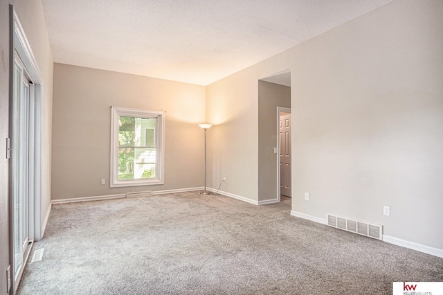 carpeted empty room featuring a textured ceiling