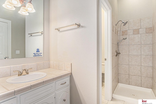 bathroom with tiled shower and vanity