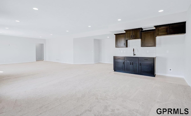 unfurnished living room featuring light colored carpet and sink