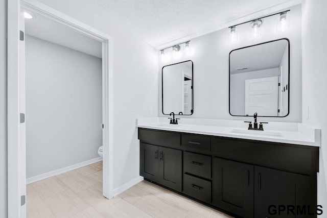 bathroom featuring vanity, a textured ceiling, and toilet