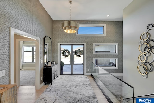 entryway with a towering ceiling, light wood-type flooring, and french doors