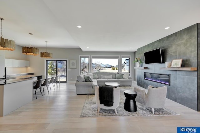 living room with a tiled fireplace and light hardwood / wood-style flooring