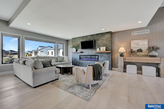 living room featuring a large fireplace and light wood-type flooring