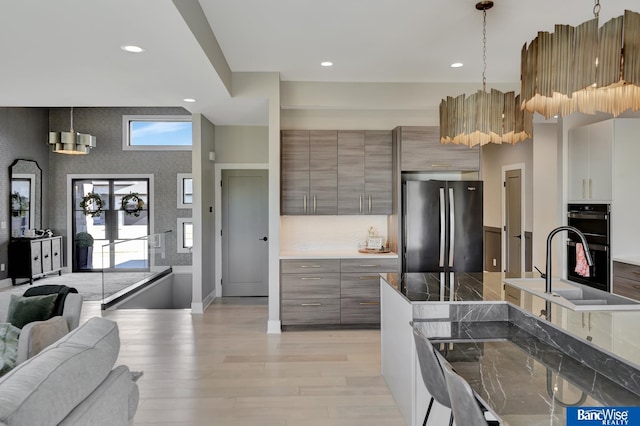 kitchen with decorative light fixtures, light hardwood / wood-style flooring, fridge, and black double oven