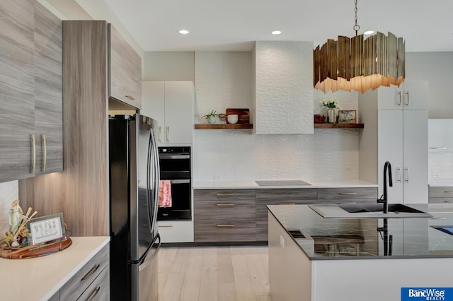 kitchen with sink, tasteful backsplash, black appliances, light wood-type flooring, and white cabinets