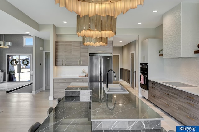 kitchen featuring hardwood / wood-style floors, sink, decorative backsplash, a center island, and black appliances