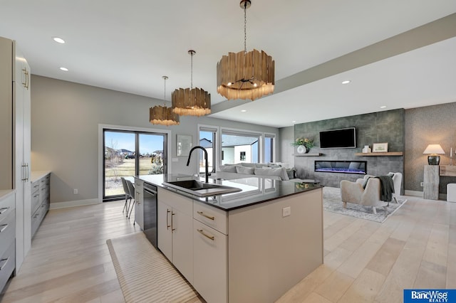 kitchen featuring dishwasher, sink, white cabinets, a kitchen island with sink, and light hardwood / wood-style floors