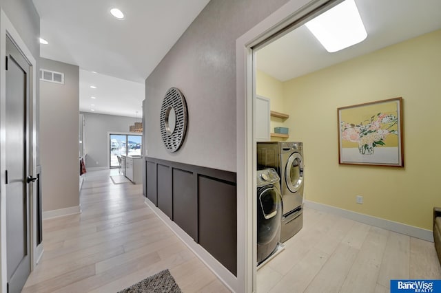 clothes washing area with light hardwood / wood-style floors and independent washer and dryer