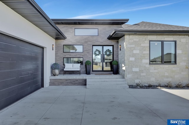 doorway to property with a garage and a patio area