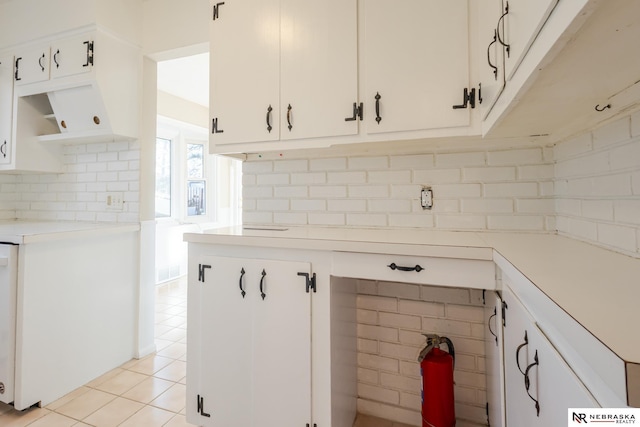 kitchen with white cabinetry, light tile patterned floors, and backsplash