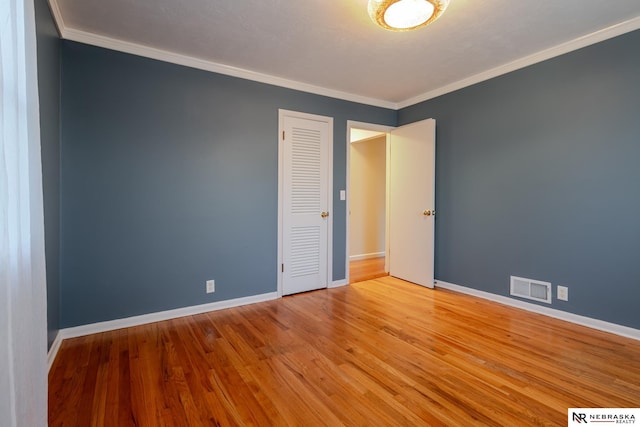 spare room with ornamental molding and light hardwood / wood-style flooring