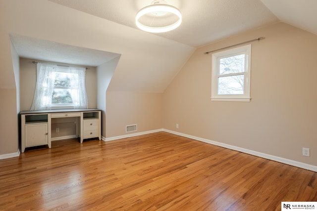 additional living space with lofted ceiling, plenty of natural light, and light hardwood / wood-style floors