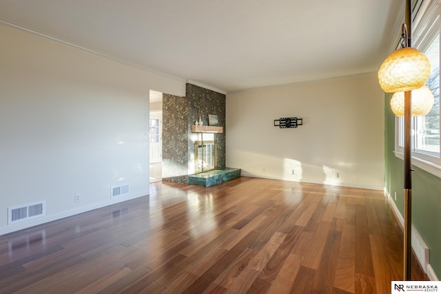 unfurnished living room with crown molding, a fireplace, and wood-type flooring