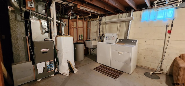 basement featuring washing machine and clothes dryer, sink, and gas water heater