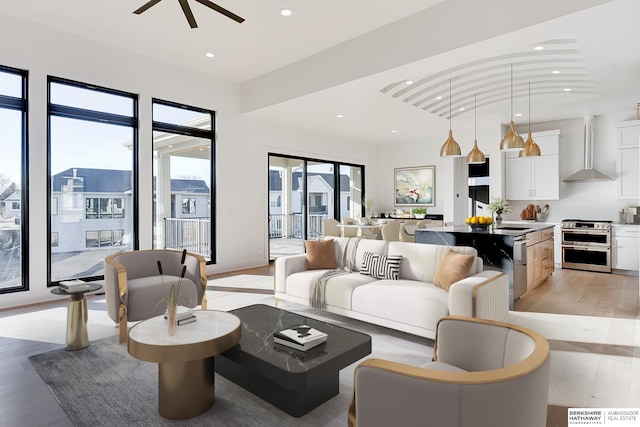 living room with ceiling fan, lofted ceiling, sink, and light hardwood / wood-style floors