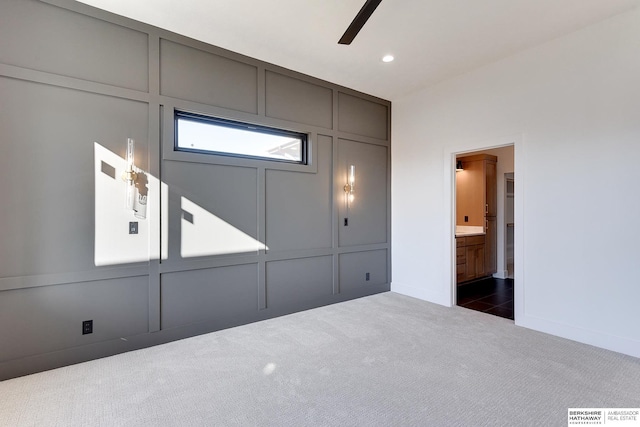 unfurnished bedroom featuring dark colored carpet, connected bathroom, and ceiling fan