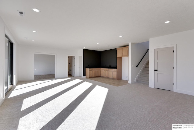 unfurnished living room featuring light carpet and wet bar