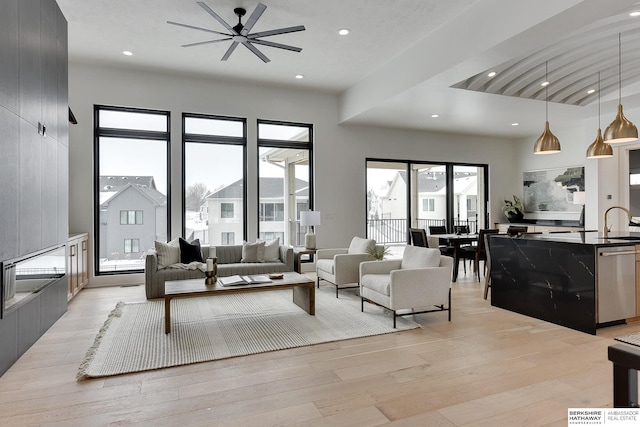 living room with sink, light wood-type flooring, and a towering ceiling