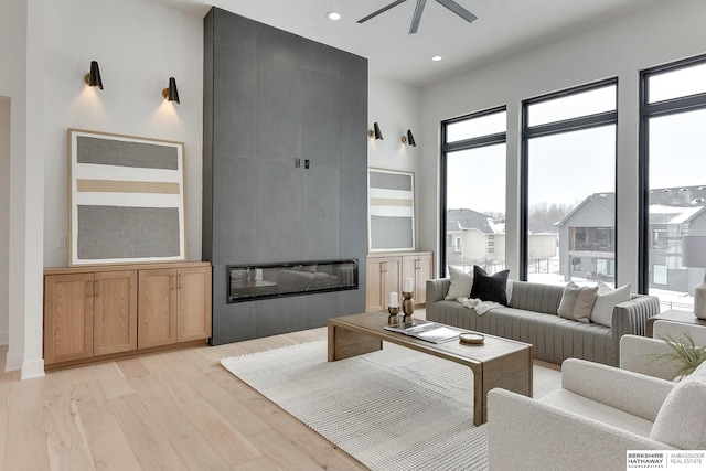 living room with ceiling fan, a fireplace, and light wood-type flooring