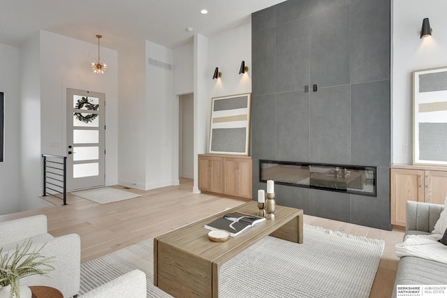 living room featuring a notable chandelier, a towering ceiling, and light hardwood / wood-style floors