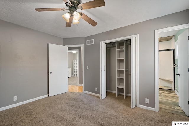 unfurnished bedroom featuring ceiling fan, a closet, light carpet, and a textured ceiling