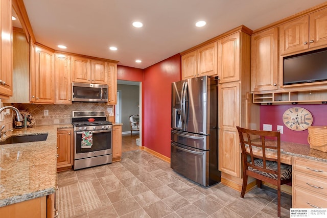 kitchen featuring sink, appliances with stainless steel finishes, backsplash, built in desk, and light stone countertops