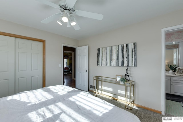 bedroom featuring ceiling fan, ensuite bathroom, dark carpet, and a closet