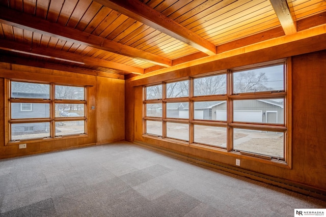 carpeted spare room with wooden walls, wooden ceiling, and beamed ceiling