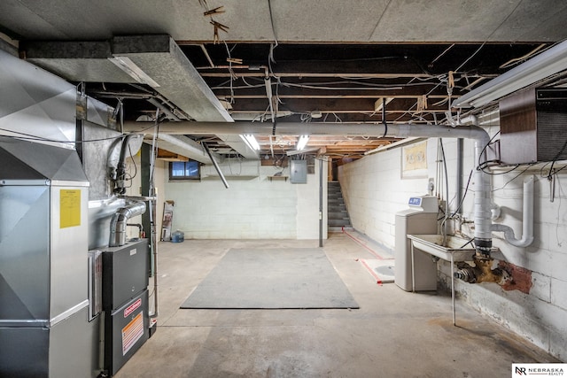 basement with heating unit, washer and clothes dryer, and electric panel