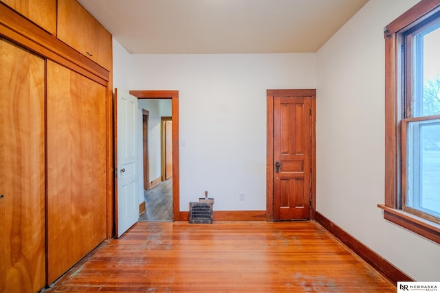 unfurnished bedroom featuring multiple windows, light hardwood / wood-style floors, and a closet