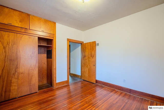 unfurnished bedroom with dark wood-type flooring and a closet