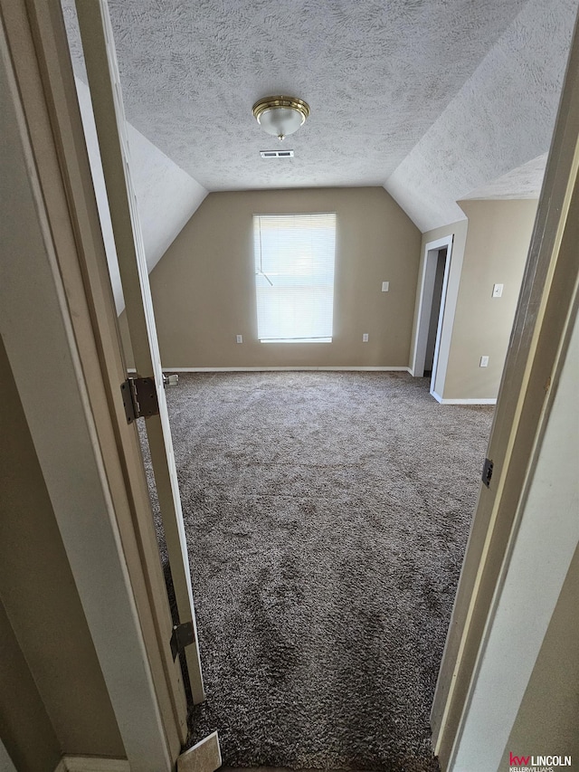 bonus room featuring carpet flooring, vaulted ceiling, and a textured ceiling