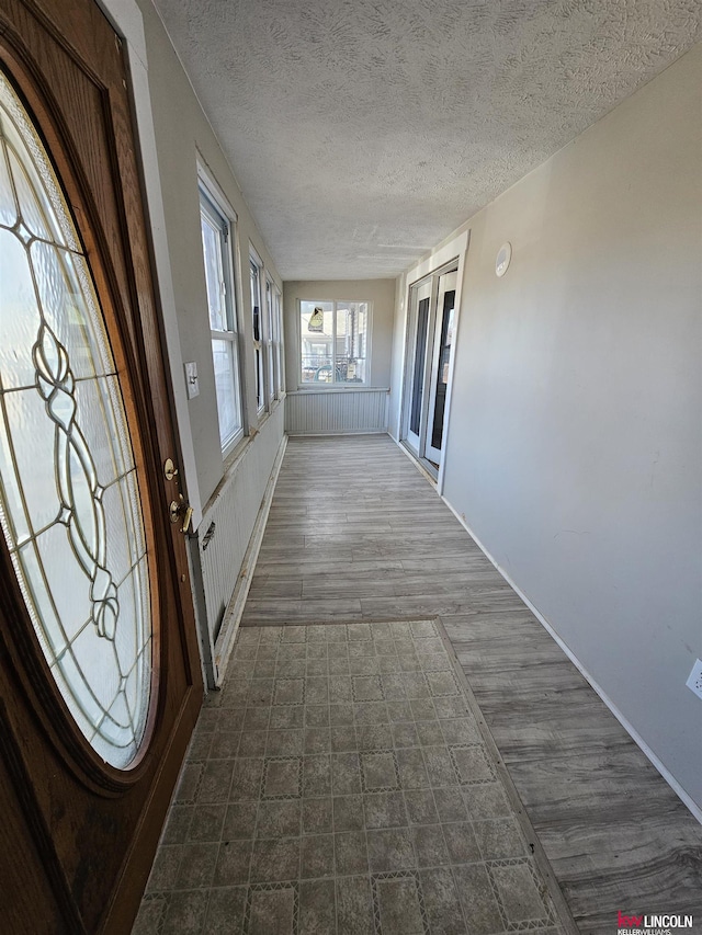 corridor with dark hardwood / wood-style floors and a textured ceiling