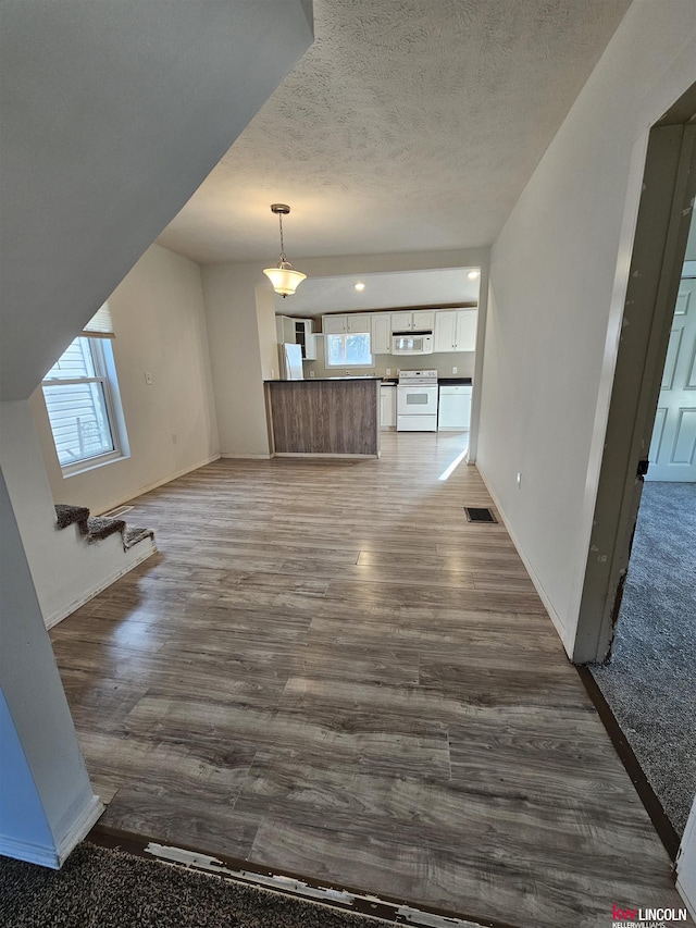 unfurnished living room with hardwood / wood-style flooring, a wealth of natural light, and a textured ceiling