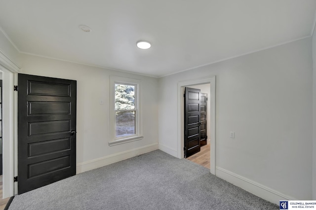 empty room featuring crown molding and light colored carpet