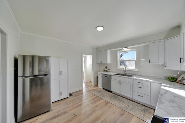 kitchen with white cabinetry, stainless steel appliances, sink, and light stone counters