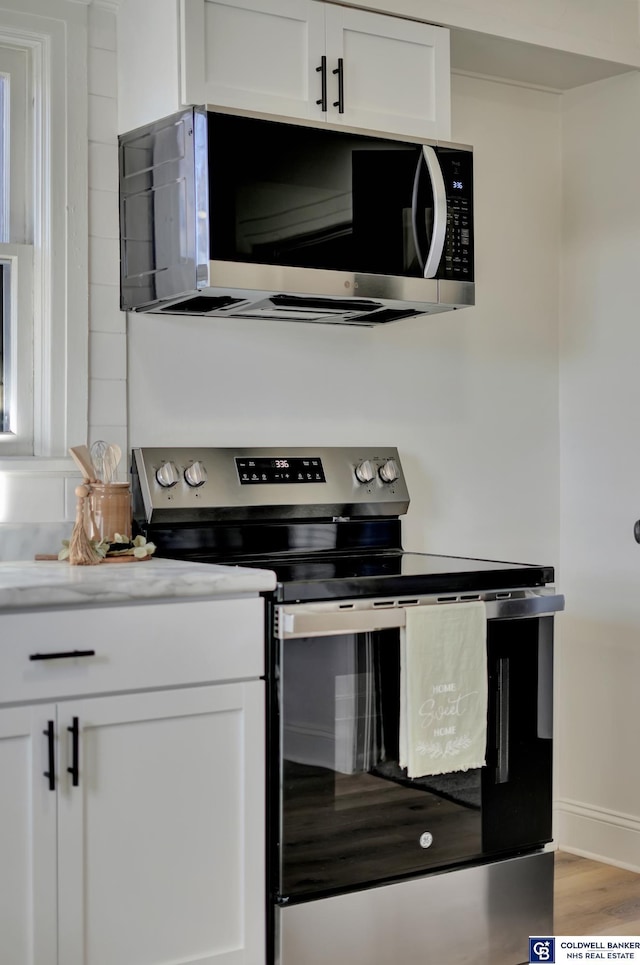 kitchen featuring hardwood / wood-style floors, stainless steel appliances, and white cabinets