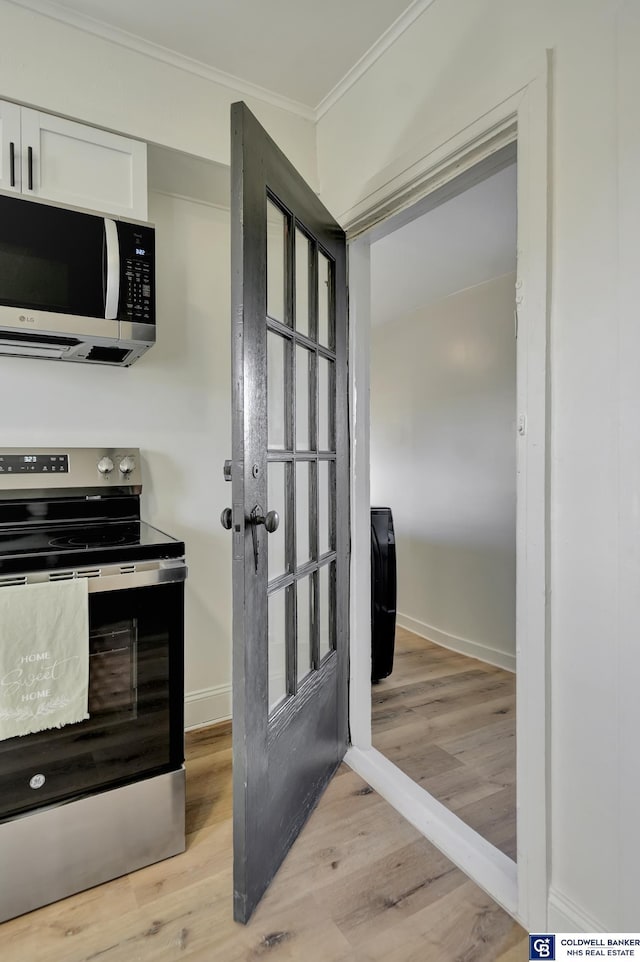 kitchen with white cabinetry, stainless steel appliances, crown molding, and light hardwood / wood-style flooring