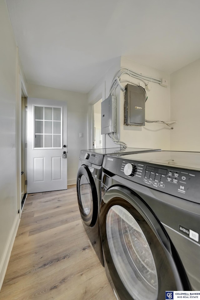 clothes washing area with electric panel, separate washer and dryer, and light wood-type flooring