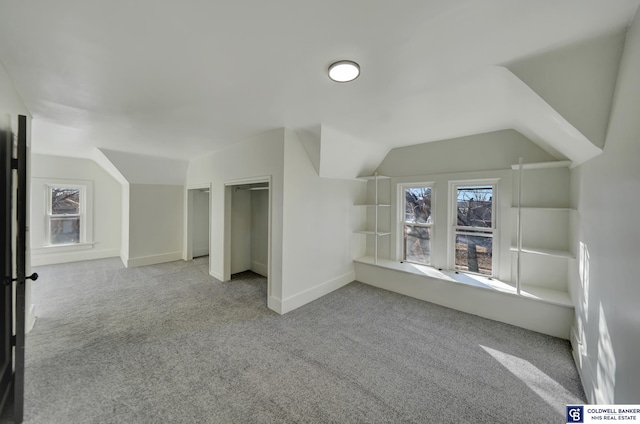 bonus room with lofted ceiling and light colored carpet