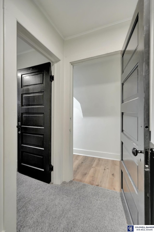 corridor with ornamental molding and light hardwood / wood-style flooring